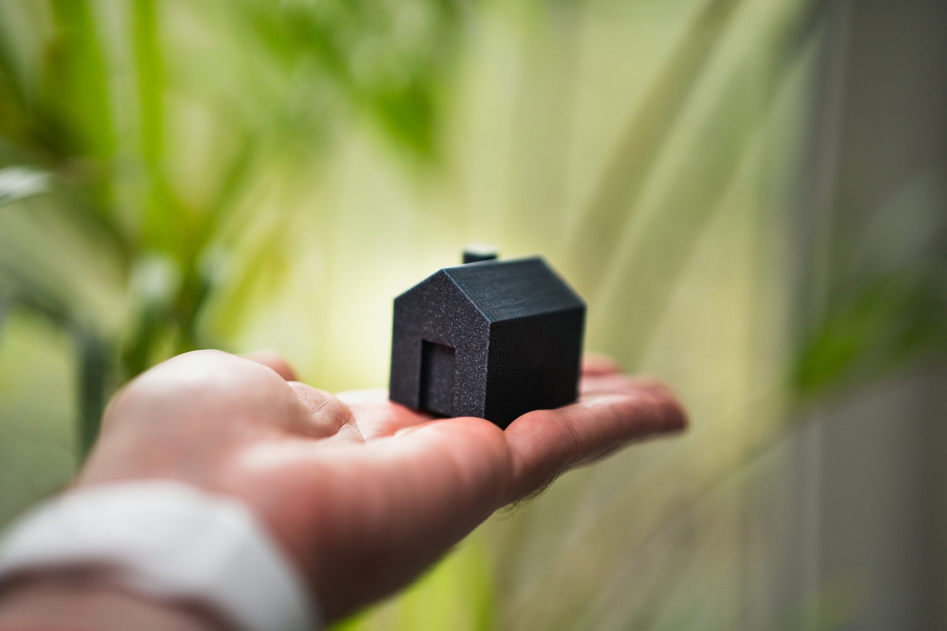 Eine Person, die ein kleines Haus in der Hand hält